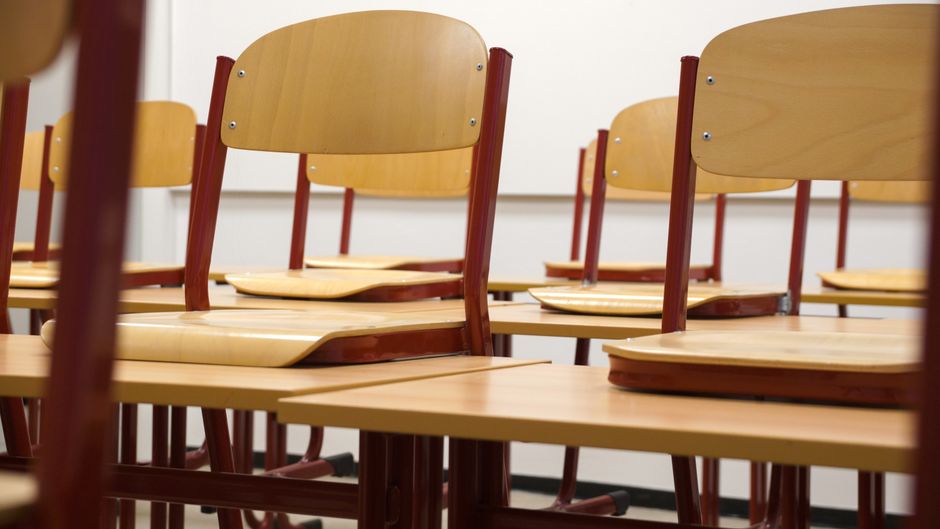A modern and empty classroom featuring wooden chairs and desks.