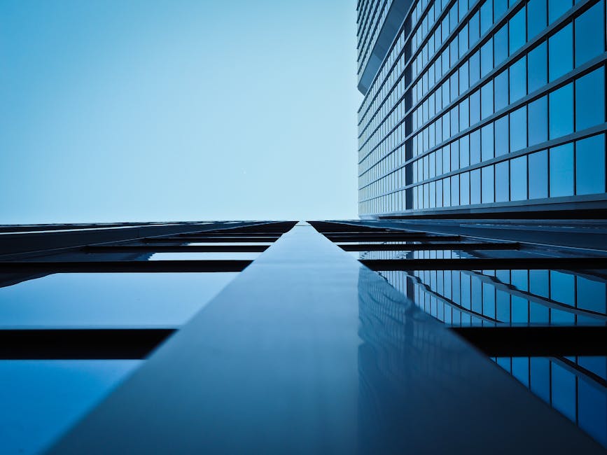 Low angle view of a modern skyscraper with reflective glass facade and blue sky